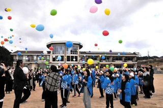 宇仁小学校の閉校記念式典で、色とりどりの風船を飛ばす児童ら＝同校