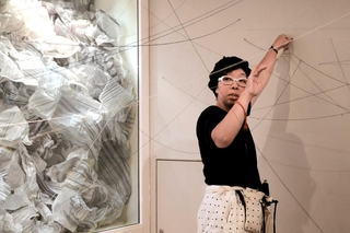 水の音が鳴り響く展示室に糸を無尽に張り巡らせるアユミ・アダチさん＝加東市上三草