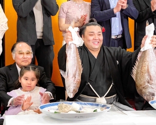 両手でタイを掲げる霧島の隣で、霧島の長女アヤゴーちゃんと写真に納まる室谷正明さん＝大阪市北区（室谷さん提供）