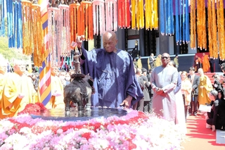 釈迦の誕生仏に水をかけて供養する国連事務総長諮問委員のドゥドゥ・ディエン博士（中央）ら＝加東市上三草