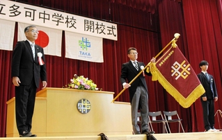 開校式での校旗授与。左は越川昌信教育長、中央は橋本衛校長＝多可中学校