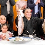 両手でタイを掲げる霧島の隣で、霧島の長女アヤゴーちゃんと写真に納まる室谷正明さん＝大阪市北区（室谷さん提供）