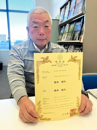 稲の再生多期作栽培方法の特許証を持つ藤田健夫さん＝小野市役所
