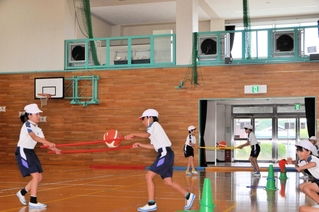 上部の室内機から冷風が吹き下ろす中、ボール運びを競う児童＝中番小学校
