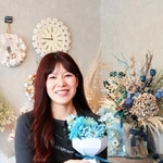 店のコンセプトカラーであるブルーの花を持つ芳原真弥さん＝加東市上滝野