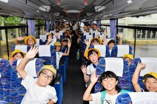 熱中症対策のバスで下校する九会小学校の児童たち＝同小