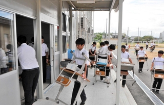 机と椅子を仮設校舎に運び込む生徒ら＝河合中学校
