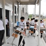 机と椅子を仮設校舎に運び込む生徒ら＝河合中学校