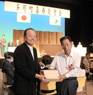 吉田一四町長（左）から記念品を受け取る参加者＝多可町中区中村町