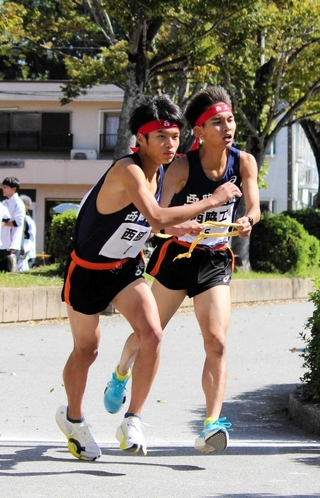 男子・西脇工の５区田渕悠真選手（右）が、６区の中川悠聖選手にたすきをつなぐ＝西脇市総合市民センター