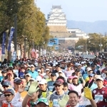 昨年の大会で、姫路城を背に笑顔でスタートするランナーら＝２０２４年２月、姫路市の大手前通り