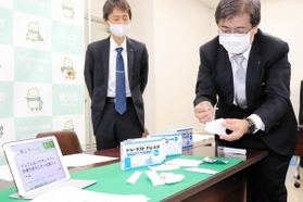 実証事業で使用する検査キットを紹介する塩野義製薬の社員＝養父市役所