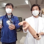 開発した筋電義手を手にする兵庫県立福祉のまちづくり研究所の陳隆明医師（右）と本田雄一郎工学博士＝神戸市西区曙町、同研究所