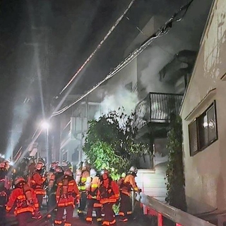 煙を出して燃える民家で消火活動をする消防隊員ら＝２８日午後６時２４分、神戸市兵庫区湊川町９