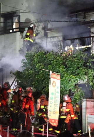 煙が上がる民家の前で活動をする消防隊員ら＝２８日午後６時２５分、神戸市兵庫区湊川町９