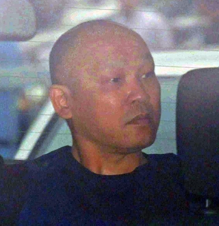 捜査車両に乗せられて長田署を出る菱川龍己容疑者＝２４日午前９時４０分、神戸市長田区北町３