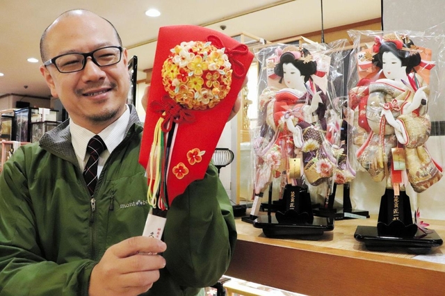 くす玉をあしらった飾り羽子板を手にする福順号店主の江戸唐音さん＝神戸市中央区雲井通５、サンパルビル１階