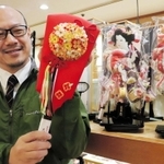 くす玉をあしらった飾り羽子板を手にする福順号店主の江戸唐音さん＝神戸市中央区雲井通５、サンパルビル１階