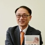 海外赴任者や企業の担当者向けの著書を持って話す関西福祉大の勝田吉彰教授＝神戸市中央区東川崎町１（撮影・中西幸大）