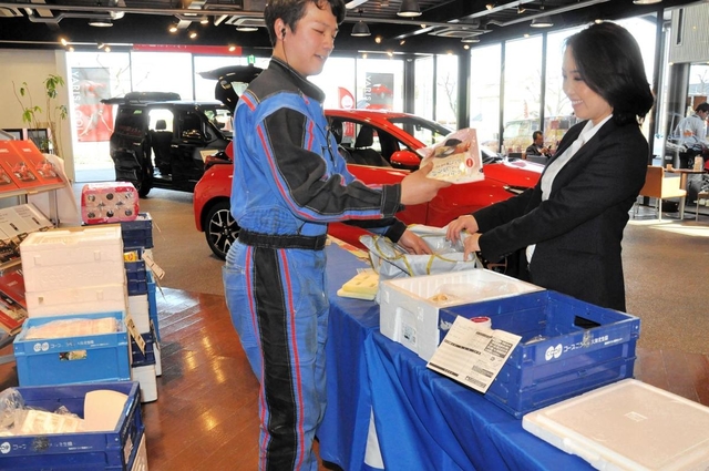 生協の商品の受け渡しに当たる作業着姿のスタッフ＝神戸市西区糀台５、ネッツトヨタ兵庫西神中央店