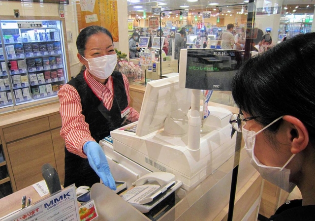 感染防止用のシートを設けたレジで接客する関西スーパーマーケットの従業員。「巣ごもり消費」で業績を伸ばした企業もあった＝伊丹市中央５