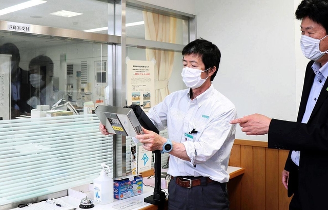 事務室の窓口に抗ウイルスランプを設置するウシオ電機の担当者ら＝たつの市新宮町芝田、兵庫県立龍野北高校