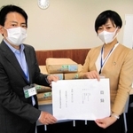 神戸市兵庫区役所の小林隆一郎区長（左）に食料品提供の目録を手渡すコープこうべの担当者＝神戸市兵庫区荒田町１