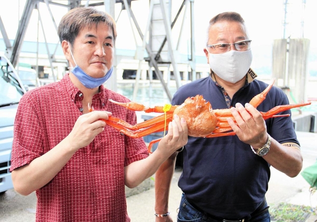 過去最高の１匹３０万円で香住ガニを競り落とした海産物販売業者と井岡弘樹さん（左）＝６日午前、香住漁港西港