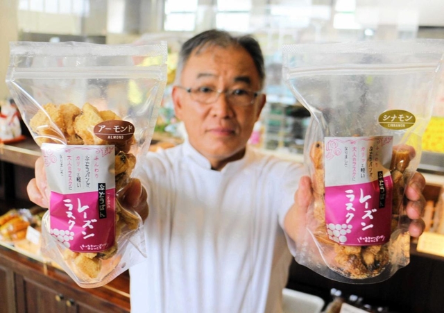 新商品「ことぶきのぶどうぱん　レーズンラスク」を手にする増成豊美さん＝ベーカリーカフェコトブキ