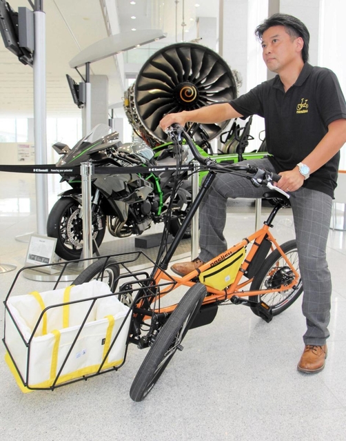 電動三輪ビークル（手前）を開発した石井宏志さん。二輪車エンジニアとして後方にあるバイクの設計にも携わった＝明石市川崎町