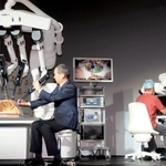 医師（右）の遠隔操作で動く手術支援ロボットの実用機。メディカロイドの田中博文副社長（左）が解説した＝東京都港区、東京ポートシティ竹芝ポートホール