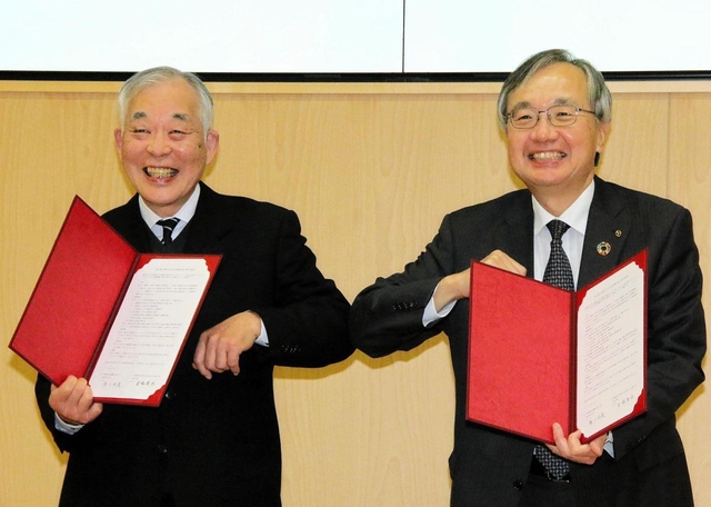 協定書を手に肘タッチをする兵庫工業会の宮脇新也会長（右）と武庫川女子大の瀬口和義学長＝西宮市池開町、武庫川女子大