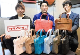 完成したかばんを手にする徳永物産の徳永尚三社長（中央）らタツノレザーの関係者＝神戸市中央区三宮町３、コモドス神戸本店