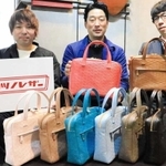 完成したかばんを手にする徳永物産の徳永尚三社長（中央）らタツノレザーの関係者＝神戸市中央区三宮町３、コモドス神戸本店