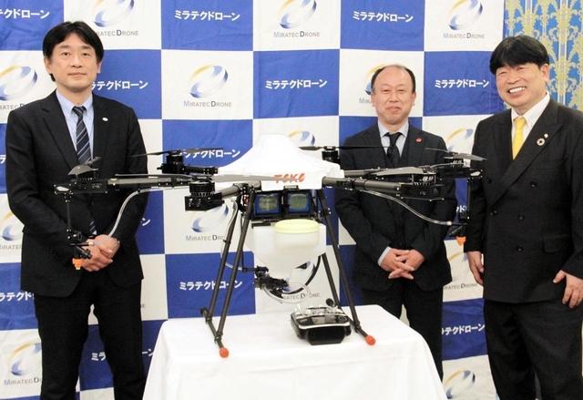 消毒に使うドローンを囲むミラテクドローンの佐々木康之社長（左）ら＝神戸市中央区港島中町６