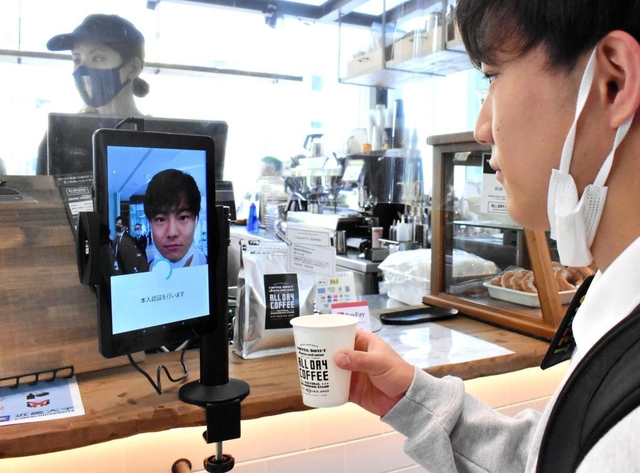 タブレット端末に顔をかざして支払いを済ませる近畿大生＝大阪府東大阪市小若江３