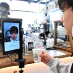 タブレット端末に顔をかざして支払いを済ませる近畿大生＝大阪府東大阪市小若江３