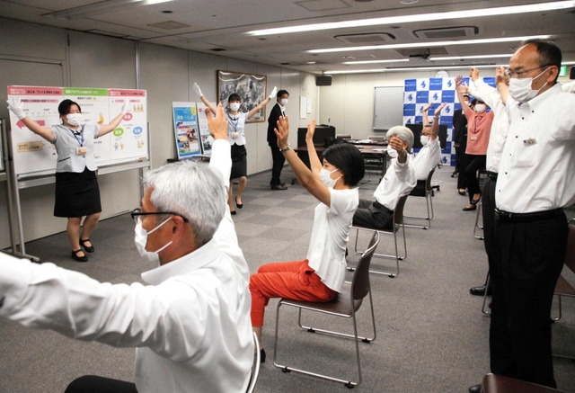 フレイル予防の模擬教室で、バスガイドがグループ会社社員らに体操を指導した＝姫路市西駅前町