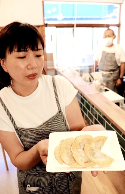 米粉の皮で包んで揚げたギョーザを手にする「餃子ＰＬＵＳ」の藤岡真理子さん（手前）＝尼崎市若王寺２