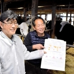 生乳の成分を分析し、健康状態が分かるチェック票を指さす酪農家の榎本安良さん（右）と、兵庫県淡路農業技術センターの生田健太郎さん＝南あわじ市神代