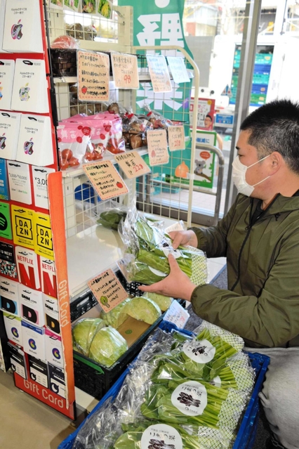 ローソン店内の専用コーナーに野菜を並べる森谷秀光さん。プロが目利きした野菜の売れ行きは好調だ＝神戸市中央区北野町３
