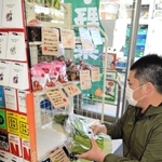 ローソン店内の専用コーナーに野菜を並べる森谷秀光さん。プロが目利きした野菜の売れ行きは好調だ＝神戸市中央区北野町３