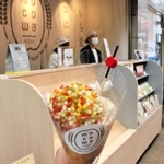 食べ歩き用カップに入ったもち麦入りのおこわと、５日にオープンする店舗＝神戸市中央区三宮町３
