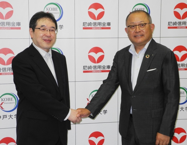 ＥＳＧ分野の共同研究が決まり、握手する尼崎信用金庫の作田誠司理事長（右）と神戸大経済経営研究所の家森信善所長・教授＝尼崎市開明町、尼崎信金