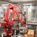 コカ・コーラのボトルが入ったケースをパレットに積み上げるアームロボット＝明石市大久保町西脇（撮影・辰巳直之）