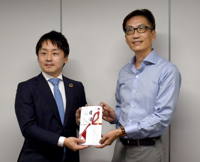 子ども食堂支援の寄付金の目録を湯浅誠さん（右）に手渡す沼田博和社長＝加古川市、神戸物産