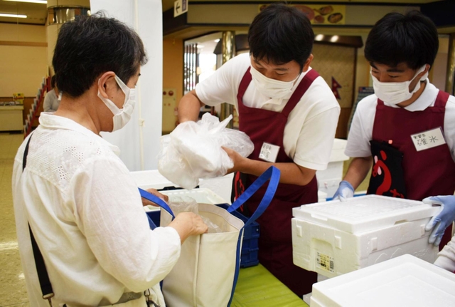 仕分けた商品を組合員に手渡す「こねくと」の利用者ら＝明石市大久保町大窪