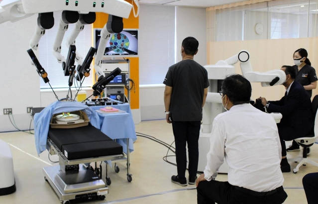 新しい訓練施設のお披露目会で、手術支援ロボット「ヒノトリ」を見学する関係者ら＝東京都新宿区