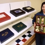 箱型に職人技の粋を集めた「漆恵」と、９代目の西銘寛子さん＝姫路市米田町、原田光明堂