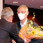 神戸広告協会の特別例会で、退任した佐藤一郎前会長（右）に花束を手渡す高梨柳太郎副会長＝神戸市中央区港島中町６、神戸ポートピアホテル